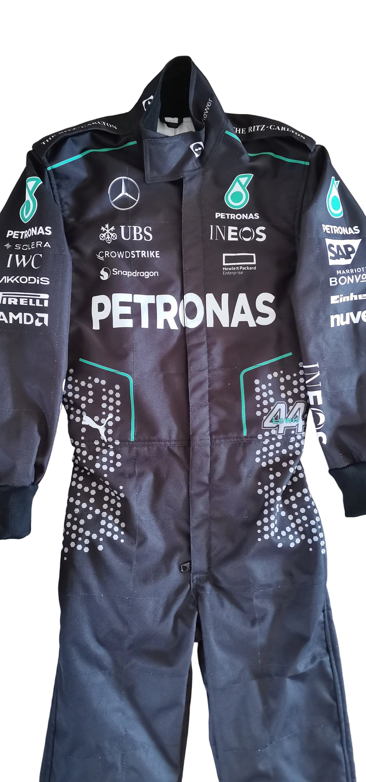 A black Mercedes Petronas Formula 1 racing suit laid flat on a beige tiled floor. The suit features multiple sponsor logos including Petronas, Mercedes, UBS, Ineos, and Puma, with teal accents and white branding.