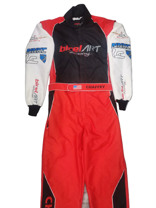 A red, black, and white full-face racing suit with sponsor logos, laid flat on a gray tiled floor. The suit features 'birElArt Racing' on the chest and 'CHAFFEY' on the waistband.